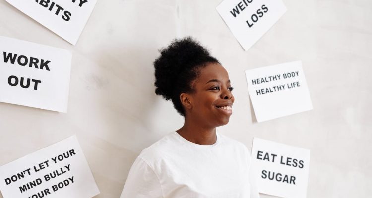 Portrait of a smiling woman surrounded by health motivation signs on a white background, promoting a healthy lifestyle.
